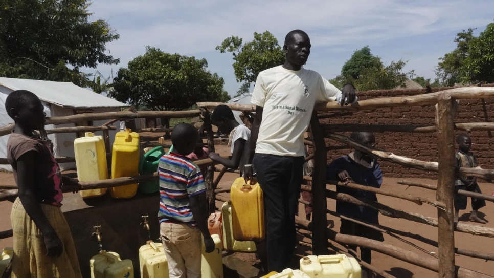 Abraham Bidal, âgé de 32 ans et originaire de la ville de Yei, au Soudan du Sud, s'approvisionne en eau pour arroser les arbres qu'il vient de planter autour de sa maison. 