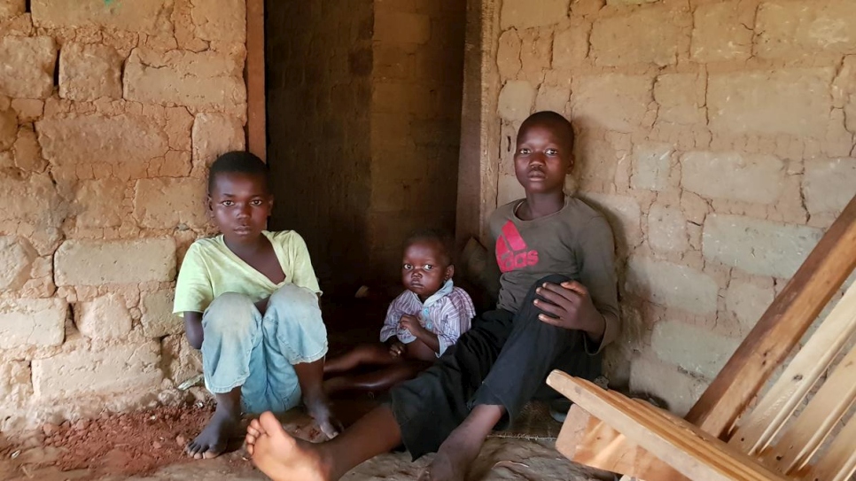 Charli (à gauche) est assis avec ses cousins devant la maison familiale au camp d'Inke, en RDC. Ils sont originaires de la République centrafricaine.

