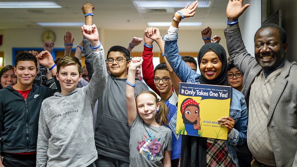 L'auteure de livres pour enfants et ancienne réfugiée somalienne Habso Mohamud pose avec des élèves lors d'une séance de lecture en public, dans une école secondaire de la région de Washington, DC. 