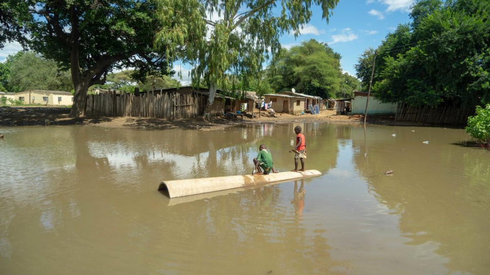 Two boys stand amid a large pool of water dumped by Cyclone Idai, at Tongogara refugee camp, Zimbabwe.