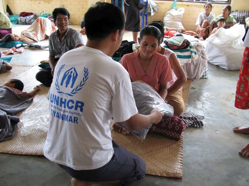 Un employé du HCR remet des couvertures à des personnes déplacées par le cyclone Nargis dans un abri temporaire à Yangon au Myanmar.