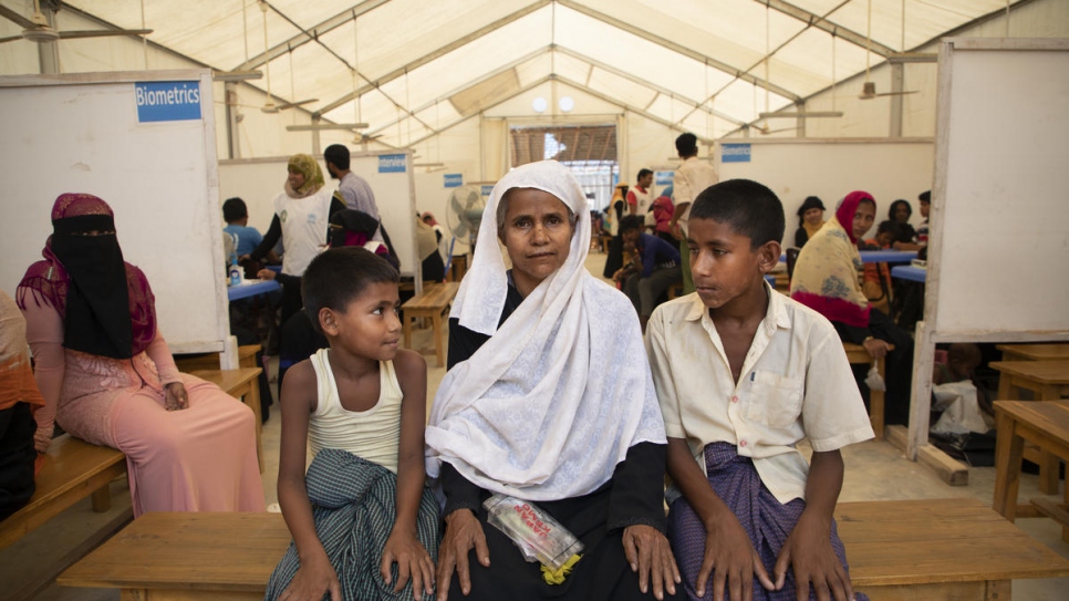 Nisa Alin, 52, sits with a grandson (left) and son at a registration centre in Kutupalong refugee camp in Bangladesh. "These documents will help us go back," says Alin, who fled violence in Myanmar in 2018.