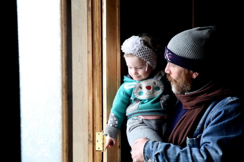 يحمل جهاد ابنته حبيبة، البالغة من العمر عامين، في منزلهما الذي تم ترميمه مؤخراً في حمص. قدمت منظمة غير حكومية محلية أبواب ونوافذ جديدة بدعم من المفوضية. 