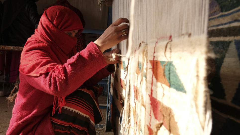 A weaver makes a carpet in Afghanistan's northern Balkh Province in December 2017. The woman and her family are displaced from Faryab province and came to Balkh in 2017.