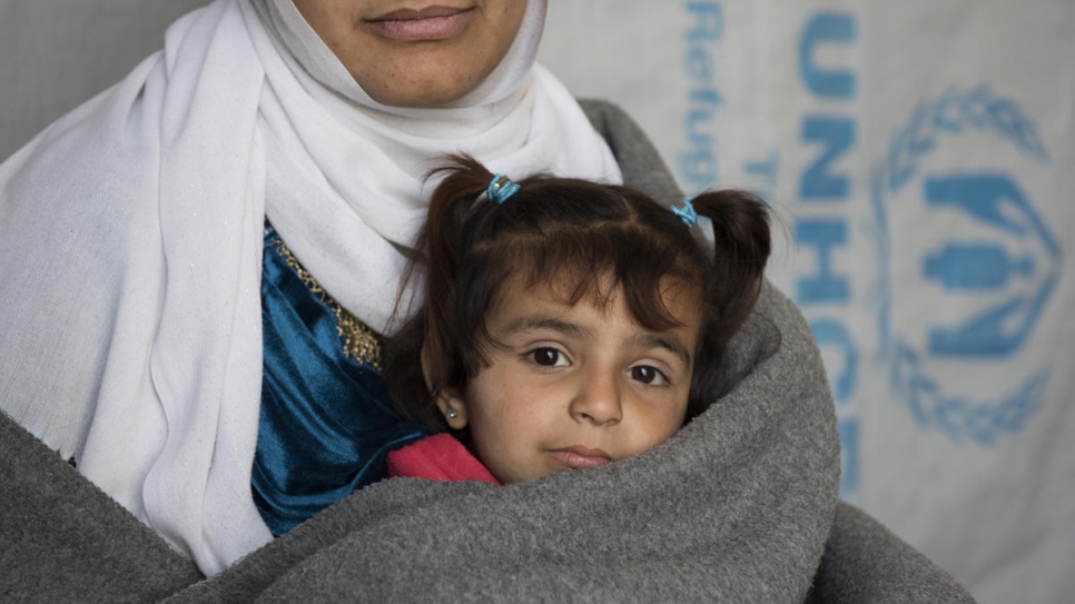 La réfugiée syrienne Amira et sa fille Amani sont photographiées dans leur maison, située dans une installation informelle de la plaine de la Bekaa, au Liban, en février 2018. La famille a construit son abri avec du bois et une bâche fournie par le HCR. 