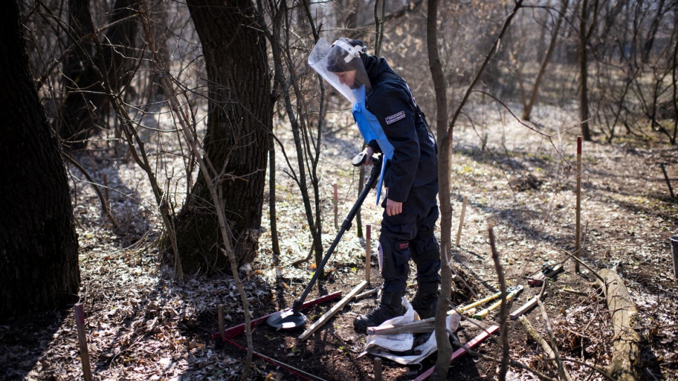 Tetiana utilise un détecteur de métal pour rechercher des mines terrestres dans une forêt située près d'Ozerne, dans le Donbass. 