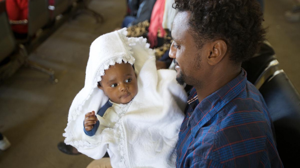 An Eritrean man proudly cradles his daughter while waiting to be evacuated to Niger.
