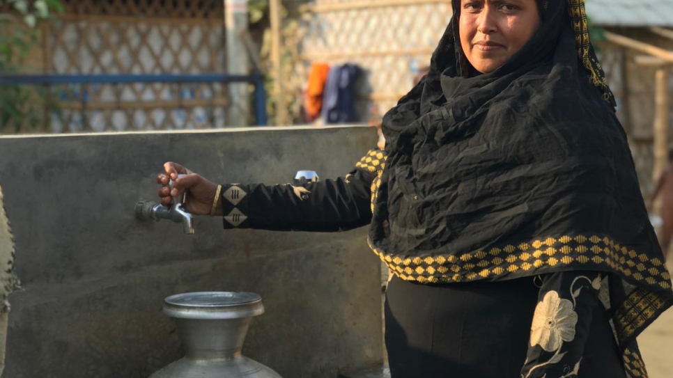 Lalu Begum, mère rohingya de 32 ans, récupère de l'eau au robinet grâce au système de distribution d'eau alimenté à l'énergie solaire, non loin de sa maison à Kutupalong, au Bangladesh. 