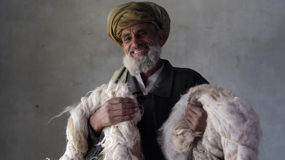 Un rapatrié afghan tient dans ses bras la laine qui servira aux fileuses. Celles-ci fabriqueront des tapis et des kilims dans le cadre d'un projet du HCR destiné à garantir des moyens de subsistance aux communautés. Kaboul, décembre 2017.