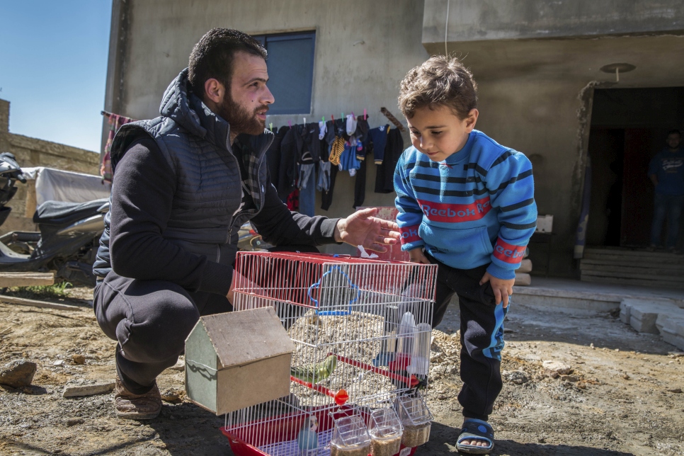 Talal, 25 ans, et son fils Ahmed, 3 ans, regardent leurs oiseaux de compagnie devant la maison inachevée où ils vivent à Zouk Bhannine, au nord du Liban.