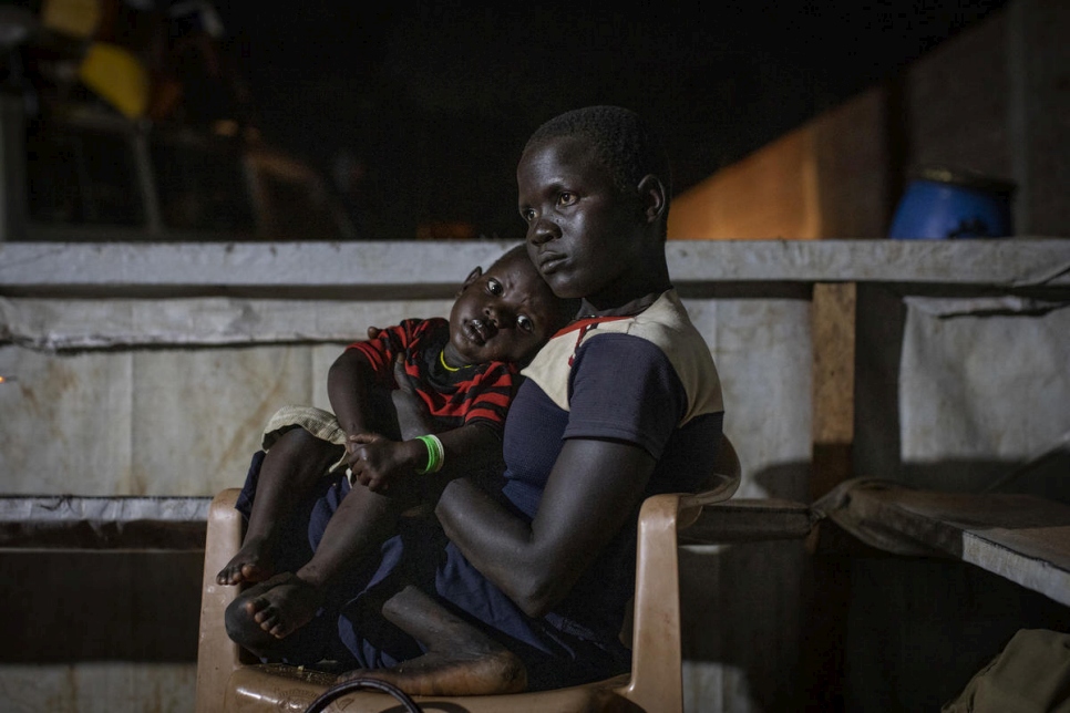 Une Sud-Soudanaise tient son enfant sur les genoux en attendant de recevoir leur repas et un hébergement dans le centre de transit d'Aru, province d'Ituri, République démocratique du Congo. 
