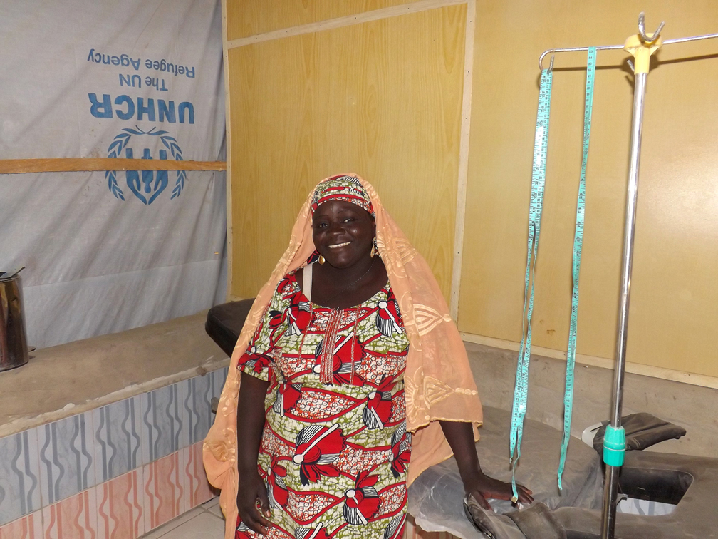 Awa poses in the small maternity room in the refugee camp. The facilities are minimal with only one delivery bed, some basic first aid equipment, and plastic sheeting for walls. © UNHCR / Louise Donavan