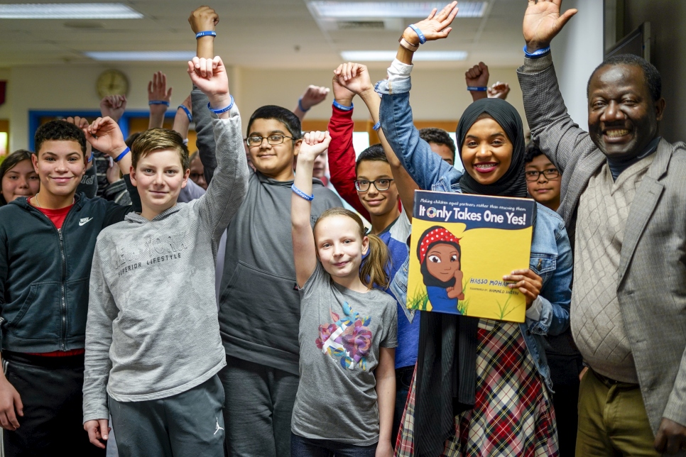 Habso Mohamud, autora de libros infantiles y ex refugiada somalí posa con estudiantes después de leer su libro en una escuela secundaria en el área de Washington, DC.