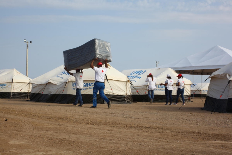 Voluntarios de instituciones locales y ONG traen colchones al nuevo centro de recepción en Maicao, Colombia.