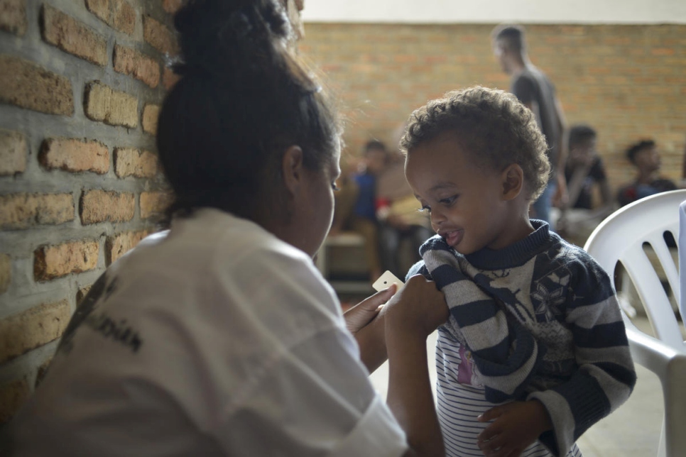 Un jeune enfant se fait mesurer l'avant-bras pendant son examen médical au Centre de transit d'urgence de Gashora, au Rwanda. 