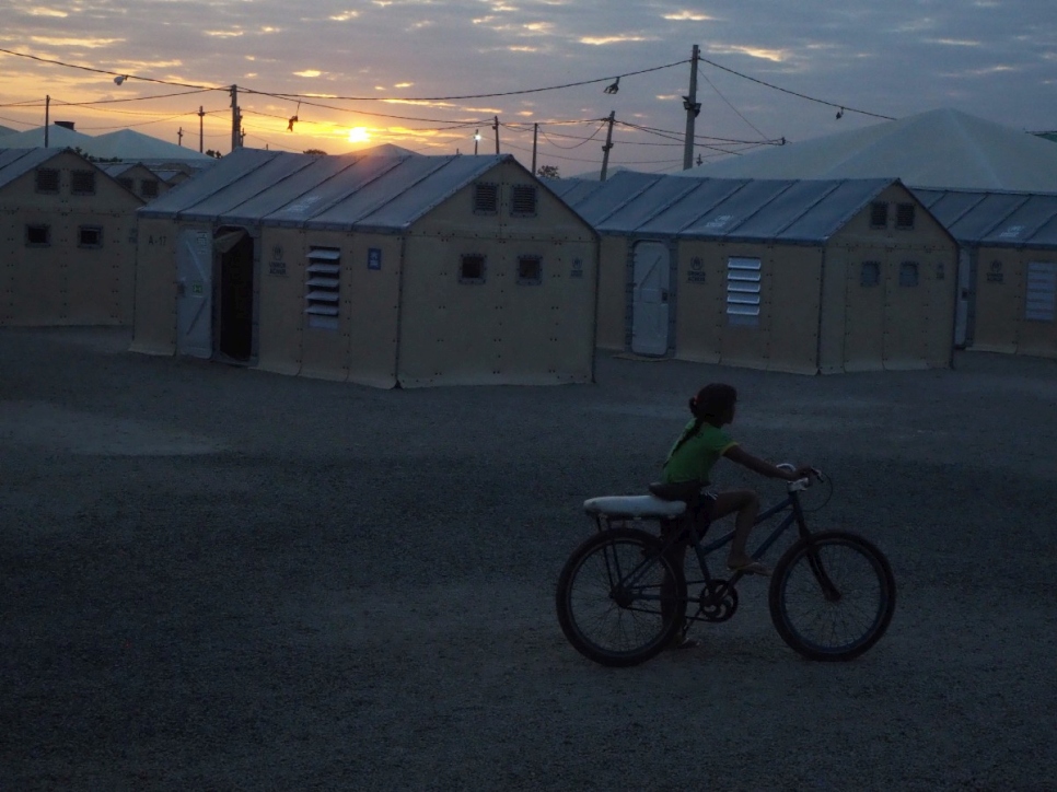 Une fillette à vélo au coucher du soleil, dans l'installation de Rondon, à Boa Vista, au Brésil. 