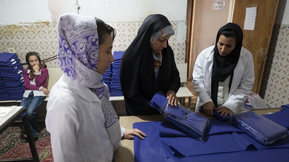 Zeynab (centre) supervises fellow Afghan refugees at her tailoring workshop in Shiraz.