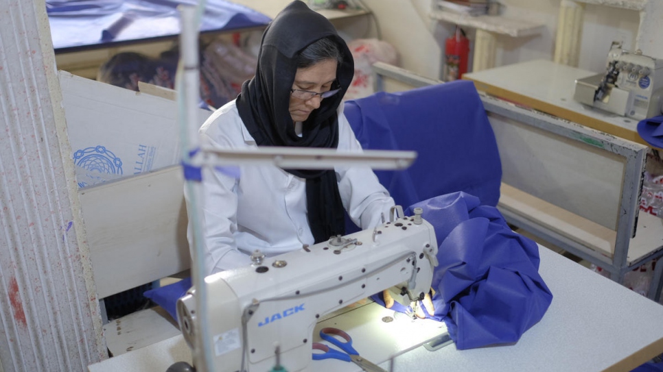 Afghan refugee Mahroo, 40, makes hospital gowns at the tailoring workshop.