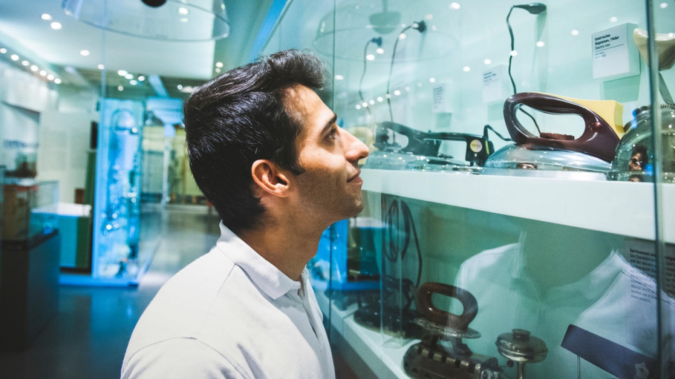 Abdul, qui était tailleur en Afghanistan, regarde de vieilles machines à coudre et des fers à repasser identiques à ceux qu'il utilisait autrefois à Kaboul. 