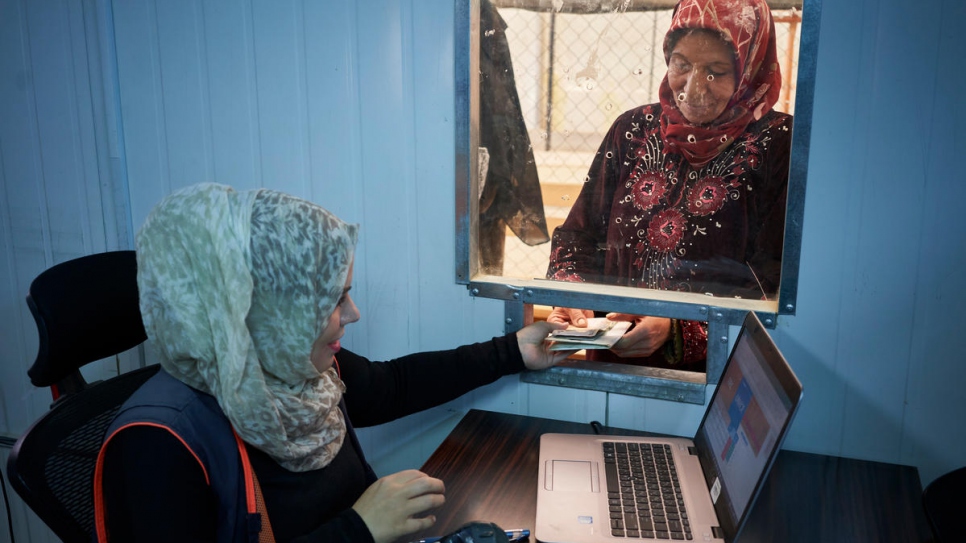 Des réfugiés syriens font la queue pour obtenir une aide en espèces pour l'équipement contre les conditions hivernales au camp de réfugiés de Zaatari, en Jordanie, en novembre 2017. L'aide permet aux réfugiés d'acheter du combustible pour le chauffage, des équipements d'isolation et des vêtements chauds.  