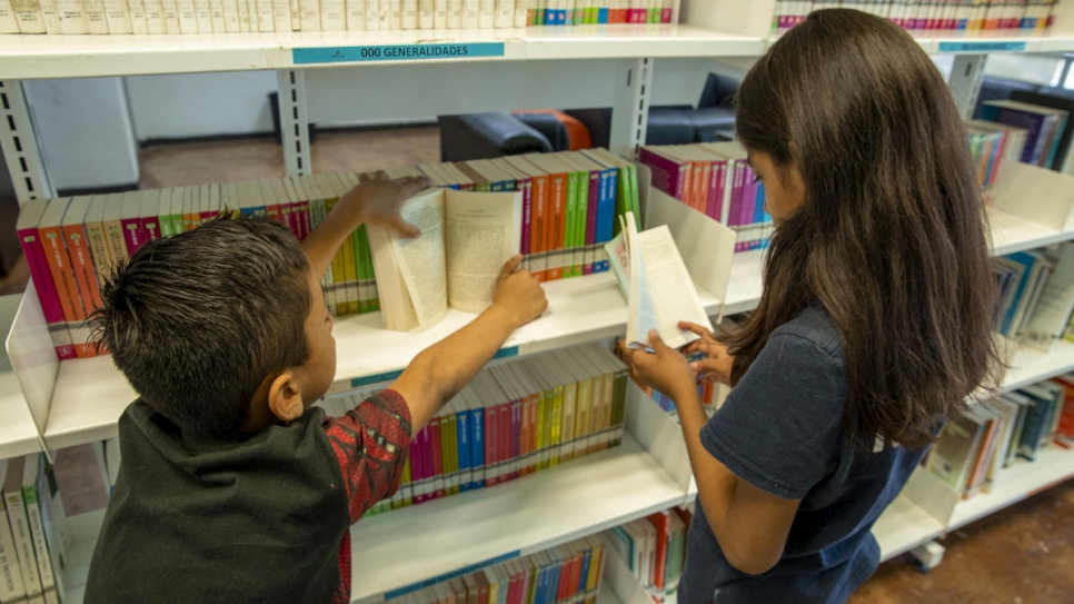 Samuel* and Maité* are checking the books inside the Biblioparque's library