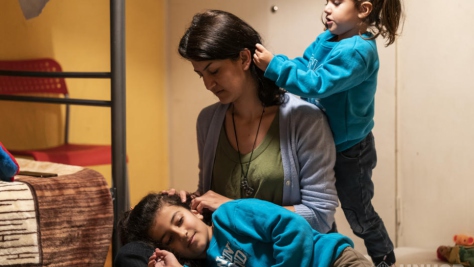 Una joven madre con sus hijas, refugiadas de Irak, juegan en la habitación que comparte la familia en un apartamento en Trikala, en Grecia.