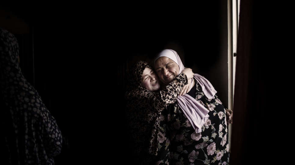 La fille de la réfugiée syrienne Haïfa Al Dallal embrasse Abir Khreisha, alors qu'elle leur rend visite chez eux à Madaba, Jordanie 