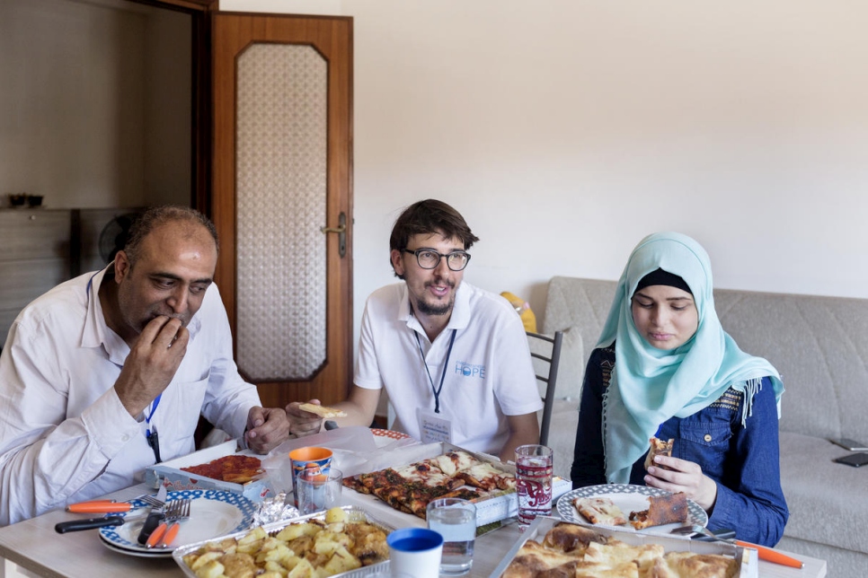 سيموني سكوتا (في الوسط) يتناول البيتزا مع عمار عيسى وسارة، 16 عاماً، بعد وصولهما إلى روما قادمين من لبنان.
