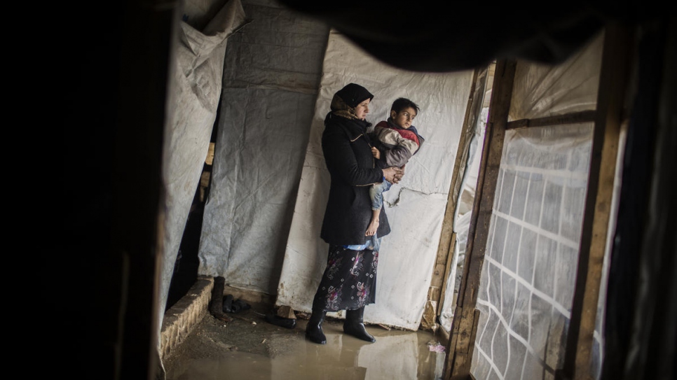 Juriya Ramadan tient l'un de ses sept enfants dans les bras alors qu'elle inspecte son abri inondé dans l'installation informelle de Dalhamiya, plaine de la Bekaa, au Liban.  