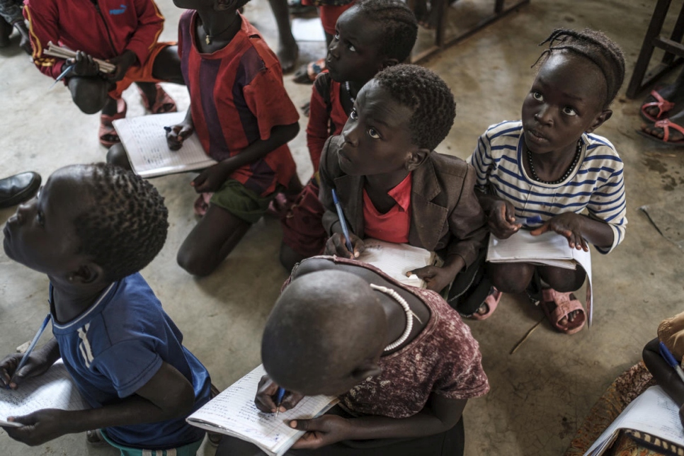 أطفال لاجئون يكتبون على دفاترهم في مدرسة جيوي الابتدائية في غامبيلا. لا يوجد ما يكفي من الكتب أو المدرسين لتلبية الطلب على التعليم. 