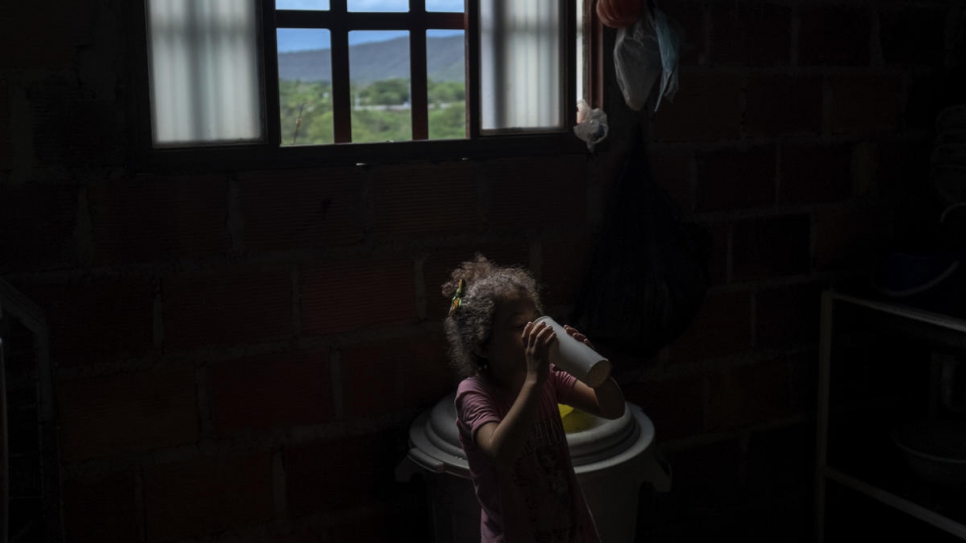 Little Yaniz, from Venezuela, drinks a glass of water inside Graciela Sanchez's home in Las Delicias community in Cúcuta.