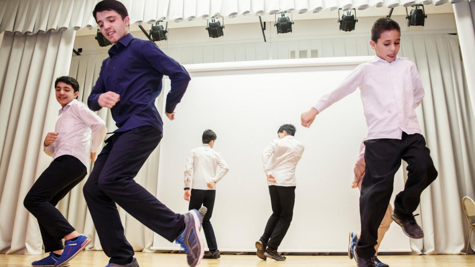 Six Afghan boys learn a traditional dance at Evrika community center.