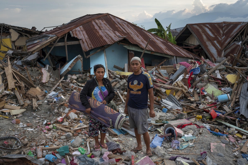 Mea (à gauche), l'une des rescapées du tremblement de terre, et son mari, sont devant les débris de la maison où elle a grandi, à Palu.