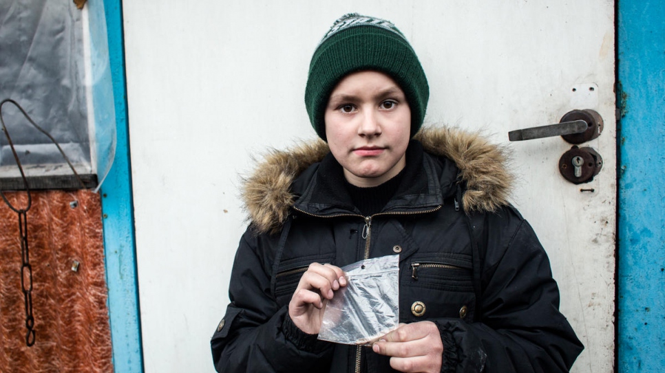 Misha holds a piece of shrapnel that was removed from his head.