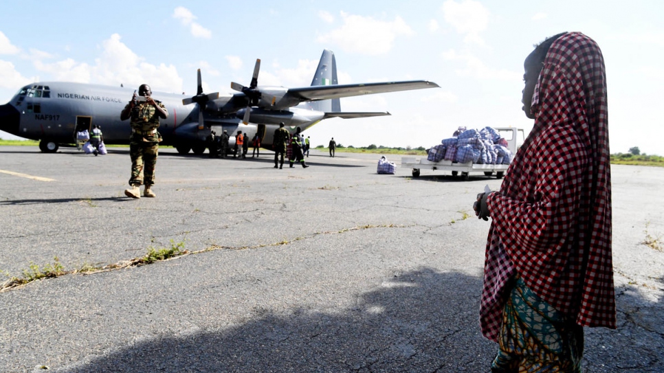 A young Nigerian refugee looks on as the plane that will take her and her family back to Nigeria waits on the runway. 