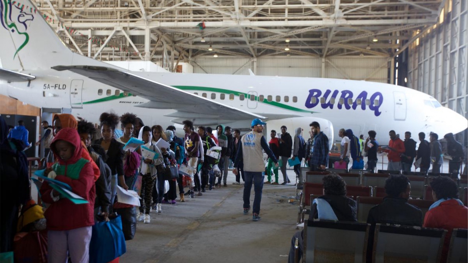 Refugees and asylum-seekers, women and children among them, wait to be flown to Niger.