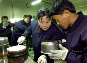 Workers check the quality of stainless steel cooking pots at an industrial park in the North Korean border city of Kaesong, Dec. 15, 2004. AFP Photo