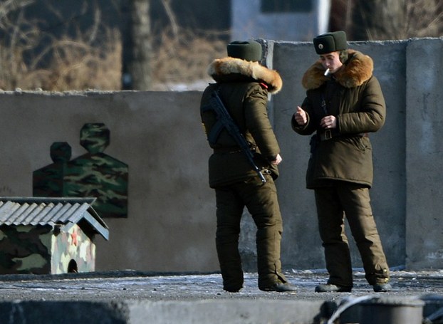 North Korean soldiers smoke cigarettes on the bank of the Yalu River across from the Chinese city of Dandong, Feb. 11, 2013.