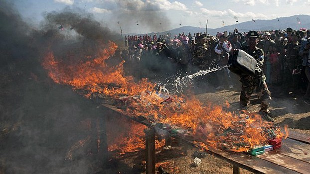 A soldier from the Ta'ang National Liberation Army burns seized drugs during a ceremony marking the 51st anniversary of Ta'ang National Resistance Day in Namhsan township, Myanmar's northern Shan state, Jan. 12, 2014.