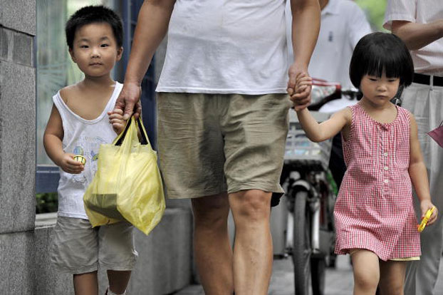 A Chinese man walks with his two children on a Shanghai street in an undated photo.