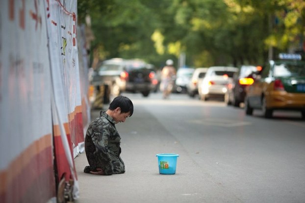 A disabled man begs on the side of a road in Beijing, Aug. 13, 2012.