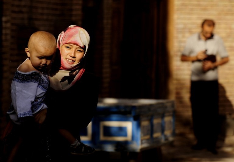 A Uyghur woman carries her child through a street in Kashgar in Xinjiang, July 10, 2009.