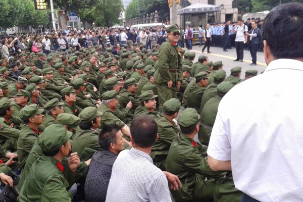 People's Liberation Army veterans sit outside the provincial government office in south central China's Hubei province, May 4, 2015.