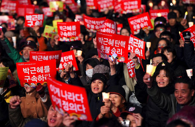 South Korean demonstrators hold up red banners reading 'Park Geun-hye impeachment, candlelight victory!' during a candlelit rally demanding arrest of the impeached-president in Seoul, March 10, 2017.