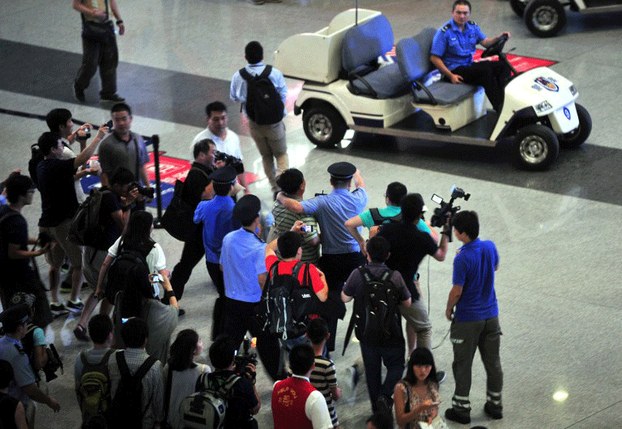 Chinese security personnel prevent media members from getting closer to the scene of the blast at Beijing's main airport, July 20, 2013.