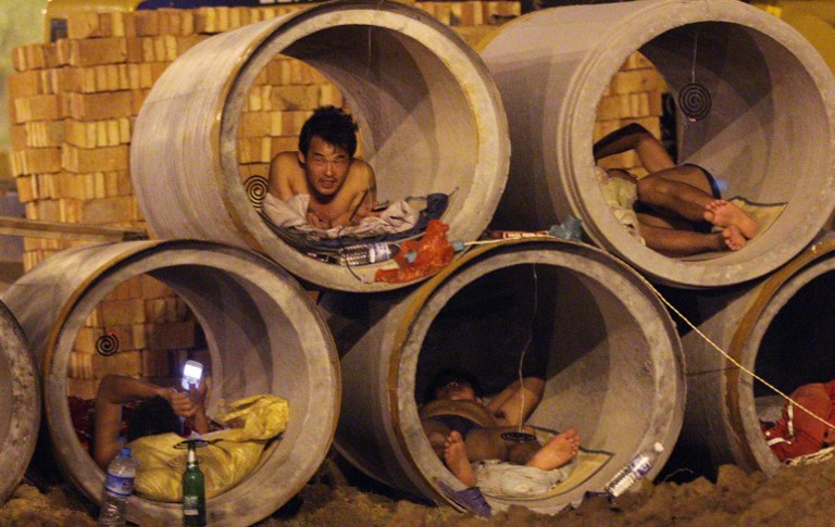 Chinese migrant workers lie in cement pipes to cool themselves down on a hot day in Shandong province, June 18, 2013.