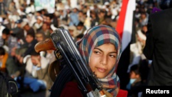 A girl carries a weapon as she attends a rally by followers of the Shi'ite Huthi movement in Yemen's capital, Sanaa, on October 26.