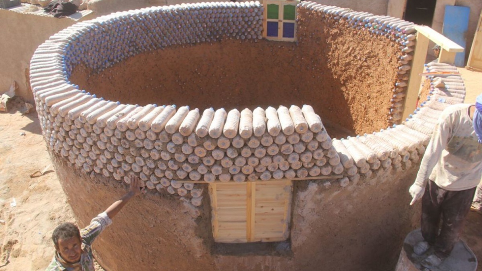 A young Sahrawi refugee builds a weather-resistant shelter out of recycled plastic bottles filled with sand at a camp in Tindouf, Algeria.