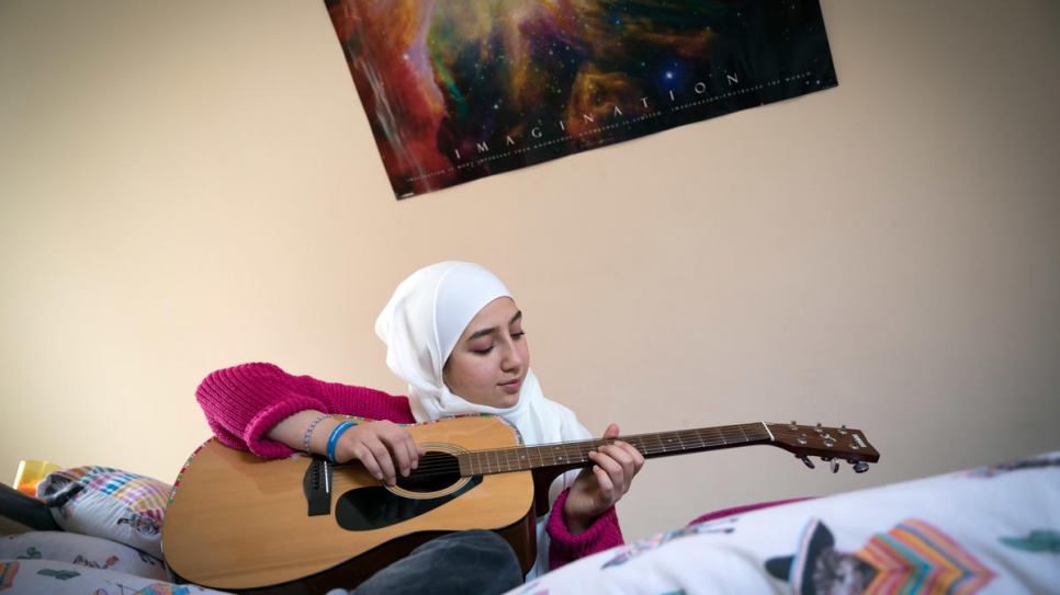 Maya Ghazal plays guitar at home in her room.