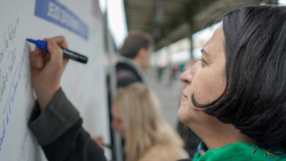 A woman signs a large poster at the launch in the train station Gare de Lyon in Paris, France.